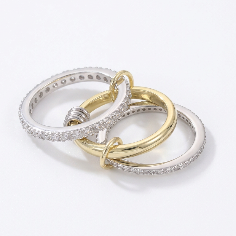Three interlocking rings in gold, silver, and white on a light gray background