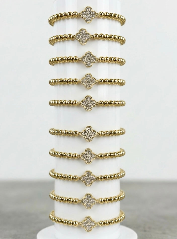 stacked gold bead bracelets with clover charm detail, layering bracelet style, boutique jewellery