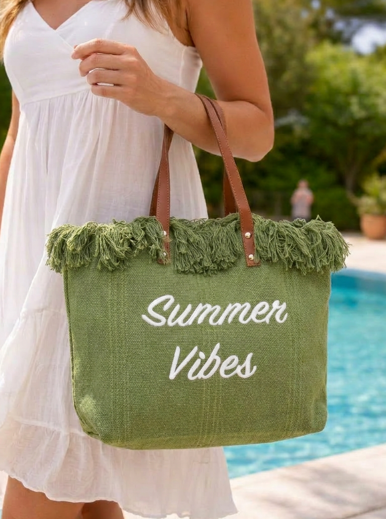 Large olive colour summer tote bag with fringe trim and shoulder straps, styled for beach vacation