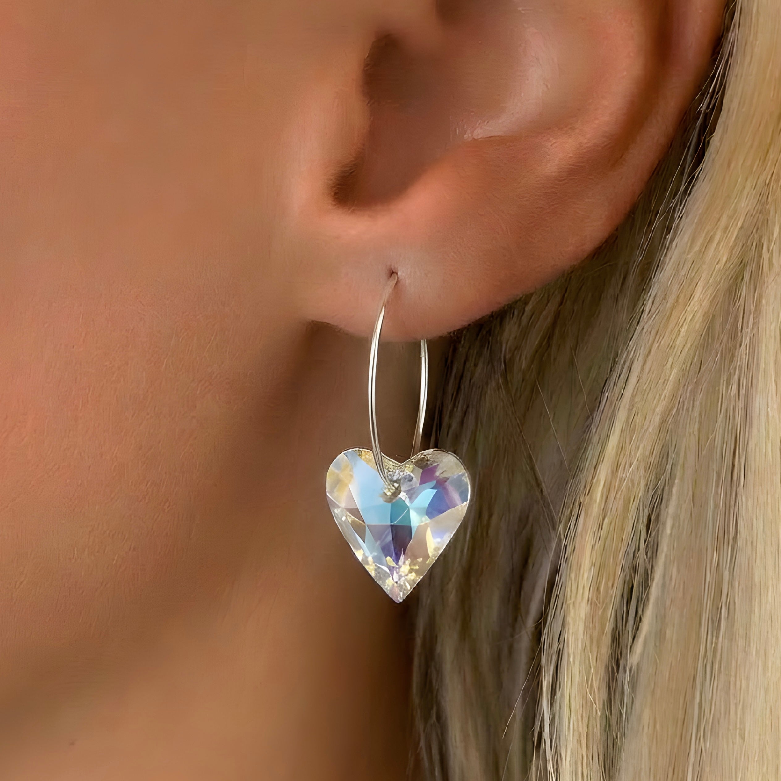 Silver hoop earrings with blue aurora crystal heart charm on ear
