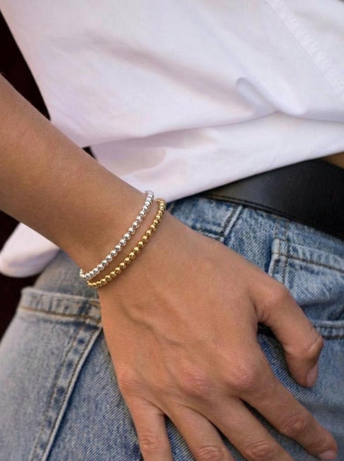 Model wearing gold and silver beaded bracelets