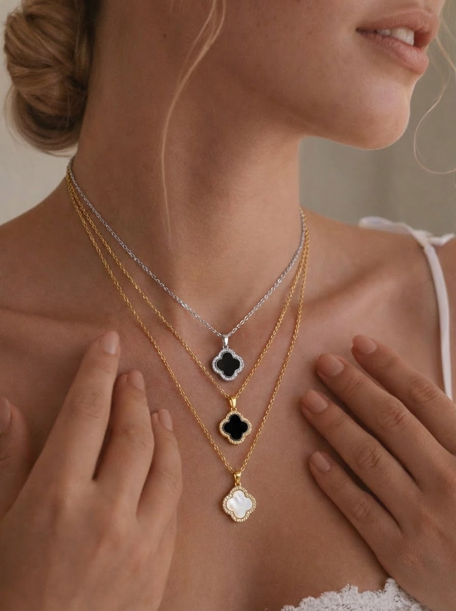Close-up of a person wearing multiple necklaces with clover pendants.