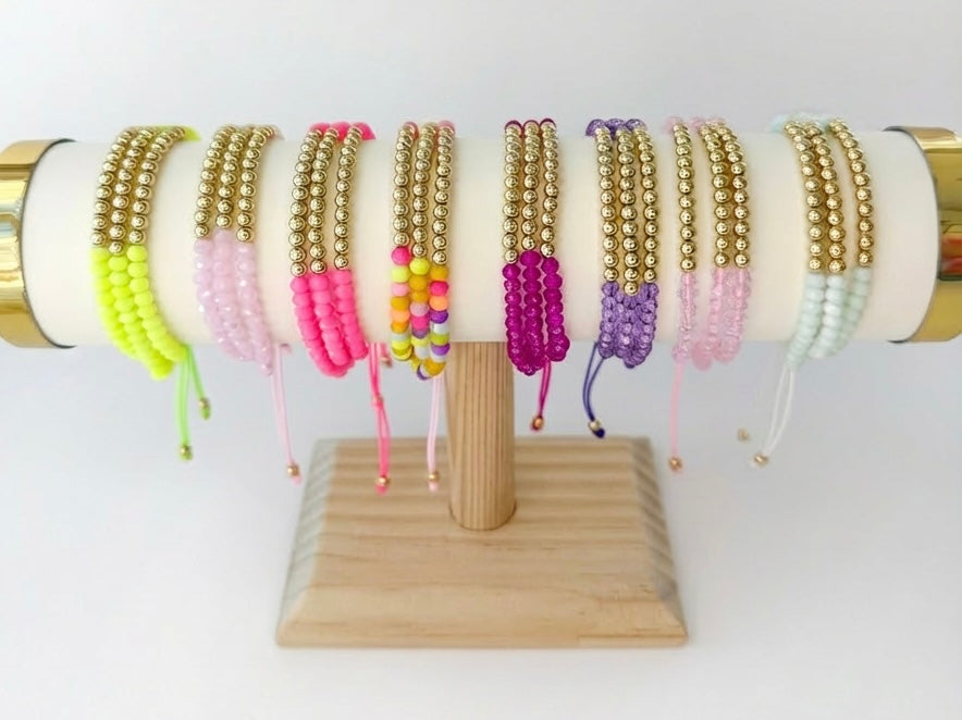 Collection of beaded bracelets on a wooden stand with a white background