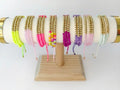 Collection of beaded bracelets on a wooden stand with a white background
