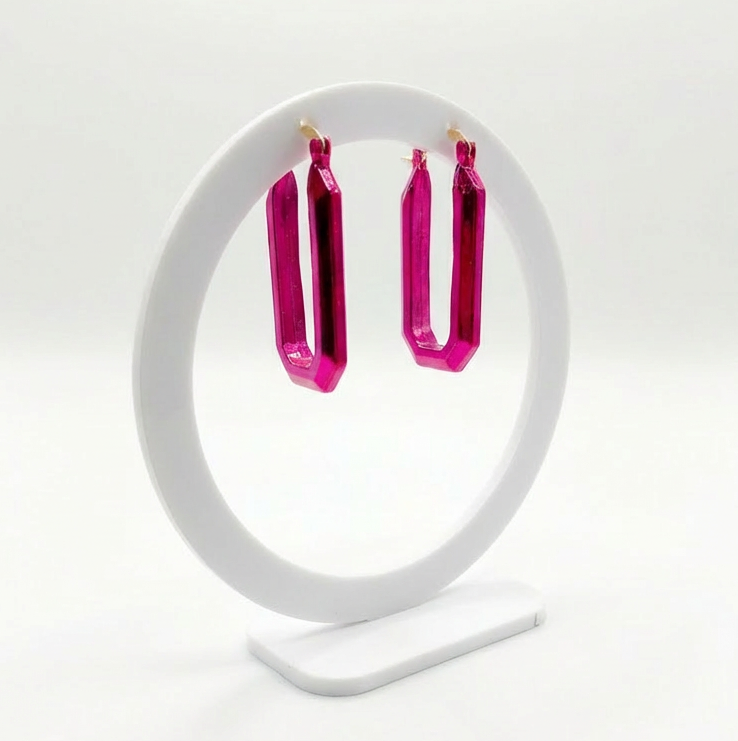 Pink hoop earrings on a white stand against a light gray background